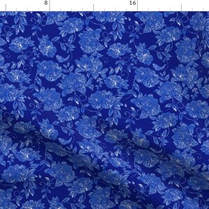 May include: A fabric with a repeating floral pattern in shades of blue and white. The design features large, stylized flowers and leaves against a deep blue background. The overall effect is a classic, elegant design.