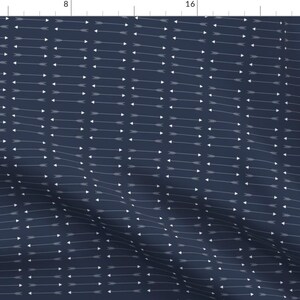 Pode incluir: Um tecido azul marinho com um padrão repetitivo de flechas brancas apontando para a direita. As flechas estão dispostas em filas horizontais.