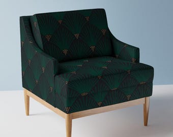May include: A dark green armchair with a repeating fan-like pattern in a lighter green and gold. The chair has a light wood frame and legs. The design is a modern take on a classic style.