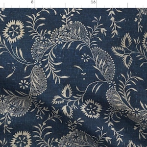 Pode incluir: Tecido azul escuro com um padrão floral creme. O design apresenta flores estilizadas, folhas e formas semelhantes a paisley. O tecido tem uma aparência ligeiramente desgastada, adicionando ao seu charme vintage. Este têxtil é adequado para vários projetos de artesanato.