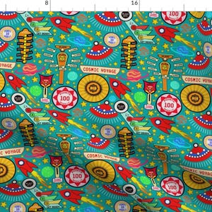 May include: A teal fabric with a repeating pattern of colorful retro space-themed illustrations. The pattern includes rockets, spaceships, planets, stars, and the text "Cosmic Voyage".