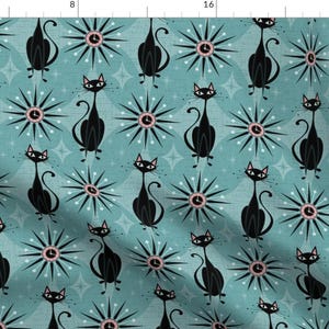 May include: A teal blue fabric with a repeating pattern of black cats and pink and white atomic clocks. The cats are stylized and have long tails. The clocks have a starburst design.