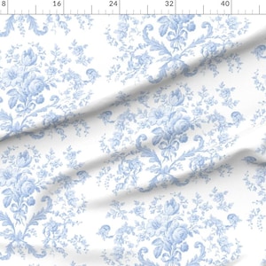 May include: White fabric with a repeating pattern of blue floral sprigs and leaves. The pattern is reminiscent of a toile design.