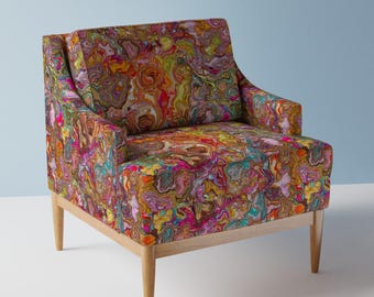 May include: A colorful armchair with a swirling, abstract pattern in shades of pink, yellow, orange, blue, and green. The chair has a wooden frame and legs.