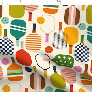 Pode incluir: Um padrão sem costura que apresenta raquetes de paddleball coloridas com vários desenhos geométricos, incluindo listras, bolinhas e estrelas. O fundo é de cor creme claro.