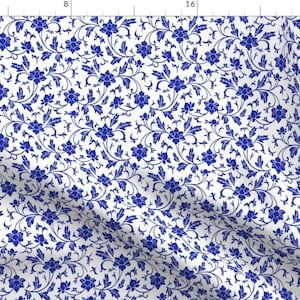 May include: A white fabric with a repeating pattern of blue flowers and leaves. The pattern is reminiscent of traditional Chinese porcelain.
