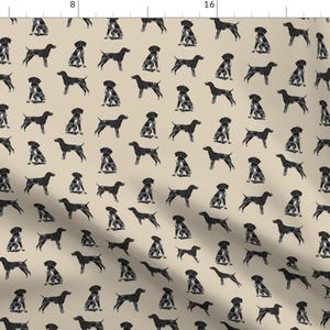 Puede incluir: Una tela beige con un patrón repetido de perros pointer alemán de pelo corto negros y blancos en varias poses. Los perros están silueteados contra el fondo beige.