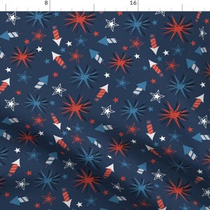 May include: A navy blue fabric with a repeating pattern of red and blue fireworks and white stars. The pattern is perfect for a patriotic theme.