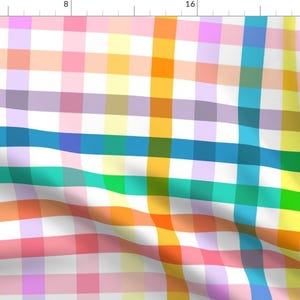 Op de afbeelding: Een kleurrijke geruite stof met een witte achtergrond en afwisselende rijen in oranje, geel, roze, paars, blauw, groen en turquoise.