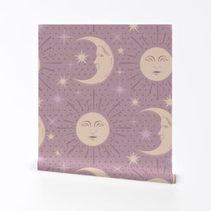 以下が含まれることがあります： 淡いピンク色の背景に白い水玉模様が施され、顔のある月と太陽が繰り返しデザインされたシームレスなパターン。月と太陽は薄いベージュ色です。