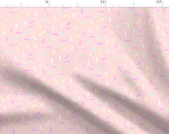 Könnte beinhalten: Ein rosa Stoff mit einem sich wiederholenden Muster aus bunten Streuseln. Die Streusel sind in verschiedenen Schattierungen von Rosa, Gelb und Grün.
