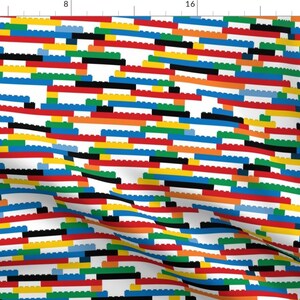 May include: A colorful fabric pattern featuring a repeating design of stacked, interlocking blocks in various colors, including red, blue, yellow, green, black, and white.