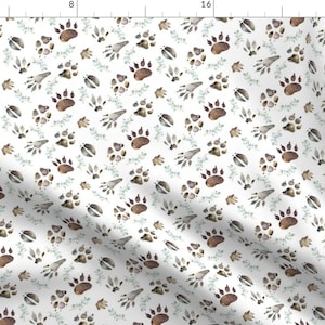Puede incluir: Un patrón sin costuras que presenta ilustraciones de acuarela de varias huellas de patas de animales en tonos de marrón, gris y blanco sobre un fondo blanco. Las huellas de patas están dispersas aleatoriamente e incluyen huellas de oso, perro y pájaro.