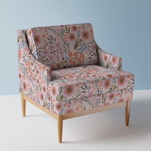 May include: A floral patterned armchair with a light pink background and a wooden frame. The chair has a high back and a wide seat. The floral pattern features pink, orange, and blue flowers.