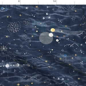 Op de afbeelding: Een donkerblauwe stof met een wit en gouden hemelpatroon. Het patroon bevat sterren, manen, planeten en wolken. De stof heeft een textuur, geweven look.