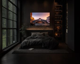 May include: A framed canvas print of the Rialto Bridge in Venice, Italy, displayed above a bed in a dark bedroom. The artwork measures 40x60 inches (102x152cm). The image shows the bridge at sunset with warm colors.