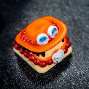 Peut inclure: Un capuchon de touche rouge et orange avec un visage blanc et bleu et un motif de cr&acirc;ne noir et blanc. Le capuchon de touche est en r&eacute;sine et est con&ccedil;u pour ressembler &agrave; un personnage d'un anime populaire.