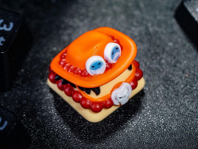 Peut inclure: Un capuchon de touche rouge et orange avec un visage blanc et bleu et un motif de cr&acirc;ne noir et blanc. Le capuchon de touche est en r&eacute;sine et est con&ccedil;u pour ressembler &agrave; un personnage d'un anime populaire.