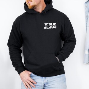 May include: Black hoodie with the word "JESUS" printed in white on the chest. The text "THE WAY - THE TRUTH - THE LIFE" is printed below the word "JESUS". The sweatshirt has a front pocket and long sleeves.