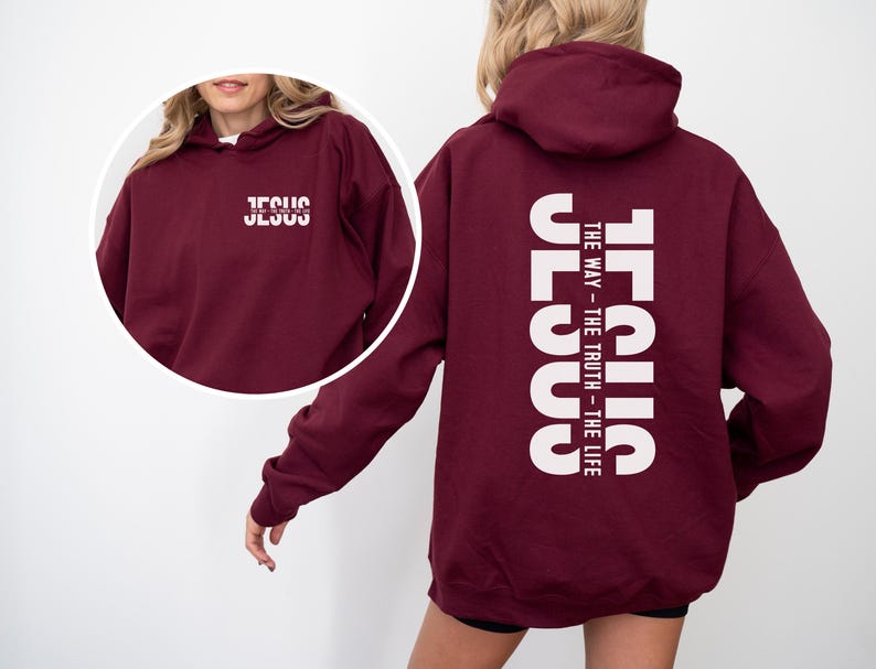 May include: A maroon hoodie featuring the word "JESUS" in white, printed vertically on the back, with the text "THE WAY - THE TRUTH - THE LIFE." The front of the hoodie also displays the word "JESUS" in white. The hoodie has a hood and long sleeves.