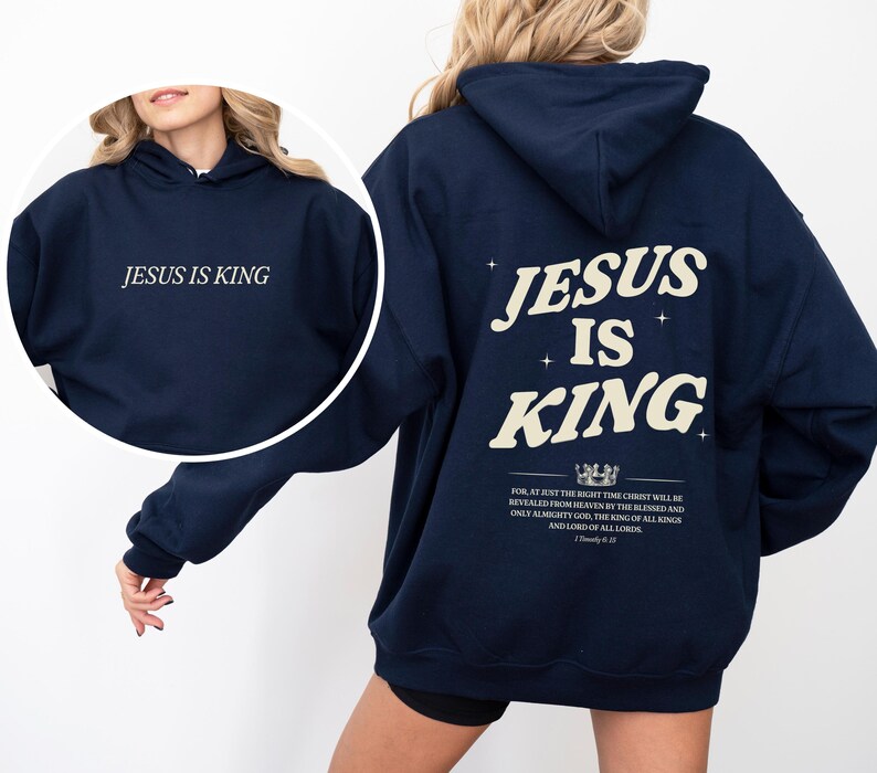May include: Navy blue hoodie with the text "JESUS IS KING" on the front and back. The back design includes the words "JESUS IS KING" in a stylized font, along with a Bible verse. The hoodie is a casual garment.