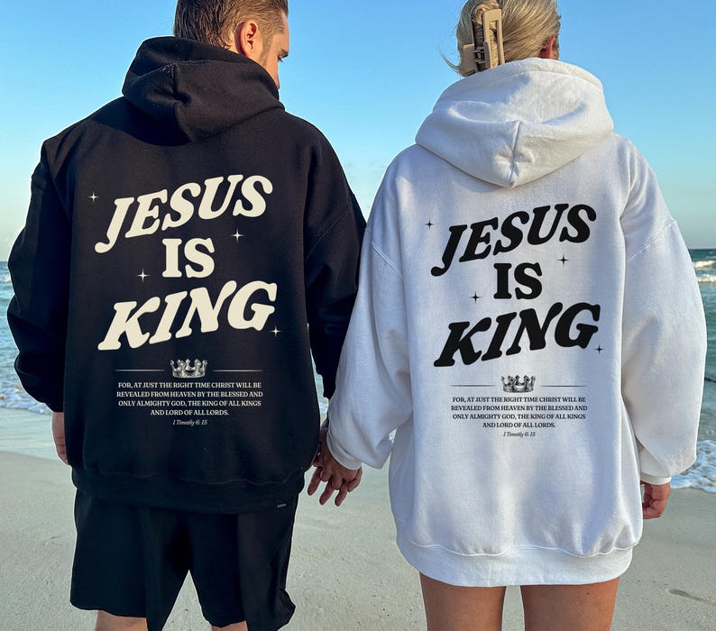 May include: Black and white hoodies with the text "JESUS IS KING" printed on the back. The hoodies also feature a quote from 1 Timothy 6:15. The image shows two people wearing the hoodies at the beach.