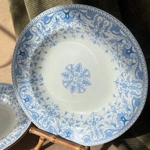 May include: Two blue and white porcelain soup bowls with a floral pattern. The bowls are stacked on top of each other and are displayed on a wooden stand.