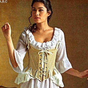 Puede incluir: Una mujer con un traje histórico, con un corsé crema con cordones de cinta, una blusa blanca con volantes y una falda larga blanca. El texto "lady diamond" es visible en la imagen.