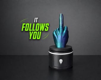 May include: A metallic blue and purple hand sculpture displaying a middle finger gesture, mounted on a black cylindrical base with a white skull icon. The text IT FOLLOWS YOU is printed in bright green letters to the left of the hand sculpture.