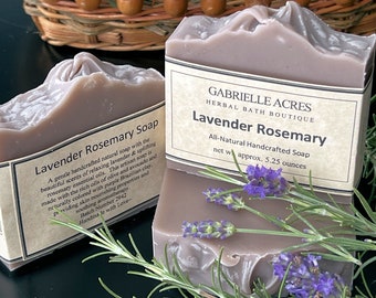 Peut inclure: Deux savons à la lavande et à la romarin, l'un empilé sur l'autre. Le savon est de couleur violet clair et a un aspect naturel et artisanal. Le savon est étiqueté "Lavender Rosemary Soap" et "All-Natural Handcrafted Soap". Le savon est entouré de brins de lavande et de romarin.