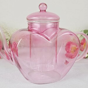 May include: A white ceramic mug with a colorful floral design. The mug features a handle and a wide rim. The flowers are in shades of pink, purple, and yellow. The mug is likely for hot beverages.