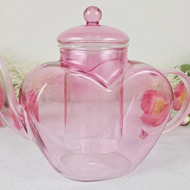 May include: A white ceramic mug with a colorful floral design. The mug features a handle and a wide rim. The flowers are in shades of pink, purple, and yellow. The mug is likely for hot beverages.