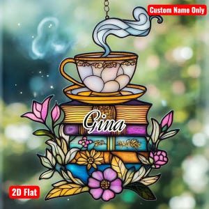 May include: A decorative stained glass ornament featuring a teacup with steam, resting on a stack of books. The ornament includes the name "Gina" and is adorned with colorful flowers and foliage. The text "Custom Name Only" and "2D Flat" are also present.