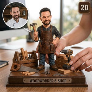 Può includere: Una statuetta bobblehead personalizzata di una persona barbuta che indossa un grembiule di pelle marrone sopra una camicia nera, mentre tiene in mano un martello. La figura poggia su una base in legno con la scritta "WOODWORKER'S SHOP" e attrezzi.