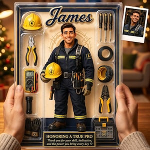 Puede incluir: Una figura de acción personalizada en un empaque etiquetado como James, que presenta una figura con un mono azul marino con rayas reflectantes amarillas, un casco amarillo y varias herramientas en miniatura que incluyen alicates, un multímetro y una caja de herramientas.