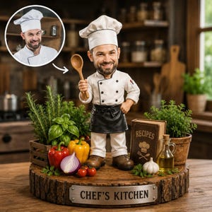 Könnte beinhalten: Eine personalisierte Wackelkopf-Figur eines Kochs in weißer Uniform, schwarzer Schürze und hoher Mütze, der einen Holzlöffel hält. Die Figur steht auf einem runden Holzsockel mit einem Metallschild mit der Aufschrift CHEF'S KITCHEN, umgeben von Gemüse und einem Rezeptbuch.