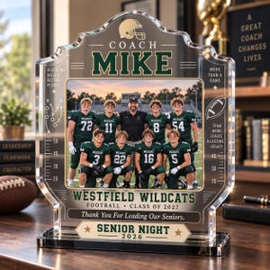 Puede incluir: Una placa de acrílico transparente con una fotografía central de un entrenador de fútbol americano y diez jugadores con uniformes verdes. La placa incluye el texto COACH MIKE, WESTFIELD WILDCATS FOOTBALL CLASS OF 2027, Thank You For Leading Our Seniors y SENIOR NIGHT 2026.