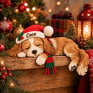 Può includere: Una scultura in carta a strati raffigurante un cucciolo di spaniel marrone e bianco addormentato, che indossa un cappello da Babbo Natale rosso con il nome Coco ricamato sul bordo bianco e una sciarpa in maglia rossa e verde, con naso nero.