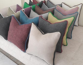 Könnte beinhalten: Eine Sammlung dekorativer Zierkissen in verschiedenen Farben, darunter Grau, Burgunderrot, Türkis und Beige. Jedes Kissen hat eine einzigartige Zierfarbe, wie Grün, Blau oder Braun, und ist auf einem neutral getönten Sofa angeordnet.
