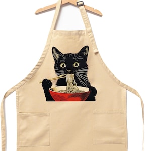 May include: A beige cotton apron with two pockets and a black cat eating noodles from a red bowl. The cat is holding chopsticks in its paws.