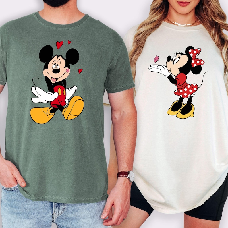 A man and a woman are standing next to each other, both wearing t-shirts with Mickey Mouse designs.
