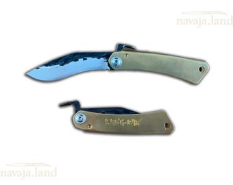 May include: Two folding knives with curved blades and brass handles. One knife is open, displaying the blade, while the other is closed. The blades have a textured appearance. The handles have a curved design and a small hole at the end.
