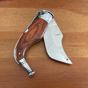 May include: A pocket knife with a wooden handle and a silver blade. The blade is open and the handle is made of dark wood with a silver accent.