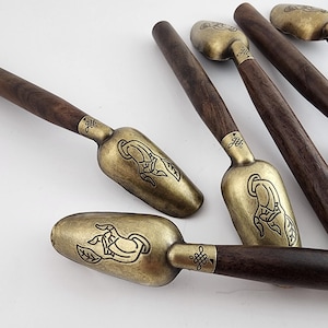 May include: Set of five wooden handled scoops with brass bowls. Each bowl features an intricate design of a hand with a leaf. The handles are dark brown wood.
