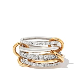 May include: A stack of five rings. Two rings are silver with a row of small, clear stones. Two rings are gold with a row of small, clear stones. One ring is silver. The rings are linked together with gold connectors.