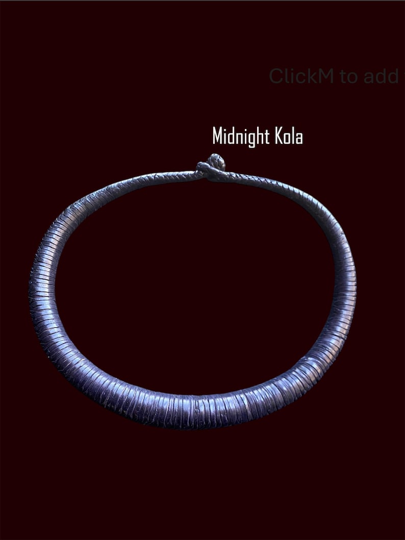 May include: A dark blue, textured necklace with the text "Midnight Kola" against a dark red background. The necklace is circular and appears to be made of a series of small, connected segments.