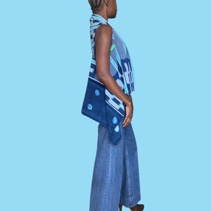 May include: A sleeveless top and wide-leg jeans. The top features a blue and white geometric pattern with a dark blue accent. The jeans are a medium wash denim. The person is wearing brown platform heels.