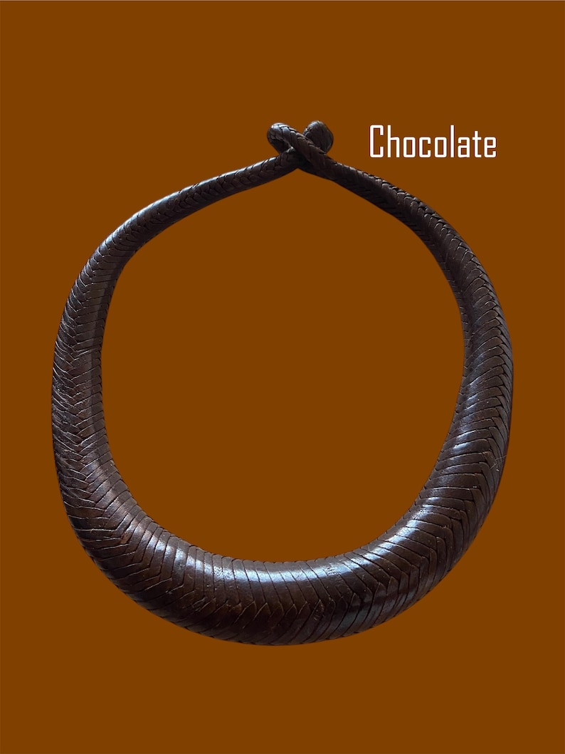 May include: A chocolate-colored, textured necklace with a circular design. The necklace is made of a woven material and features a knot closure. The word "Chocolate" is displayed in white text.