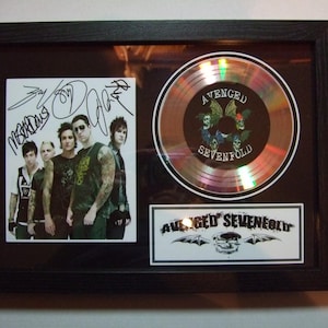 Peut inclure: Cadre noir contenant des souvenirs du groupe Avenged Sevenfold. Il comprend une photo du groupe, un CD et un logo. Le CD affiche le nom et le logo du groupe.