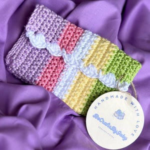 May include: A multi-colored crocheted pouch with a white crocheted trim. The pouch has a tag that says "Handmade with Love" and "BeCraftyBaby Crochet Pieces".